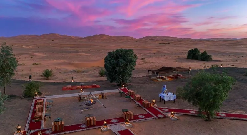 Desert camp and dunes under a pink and purple evening sky in Merzouga