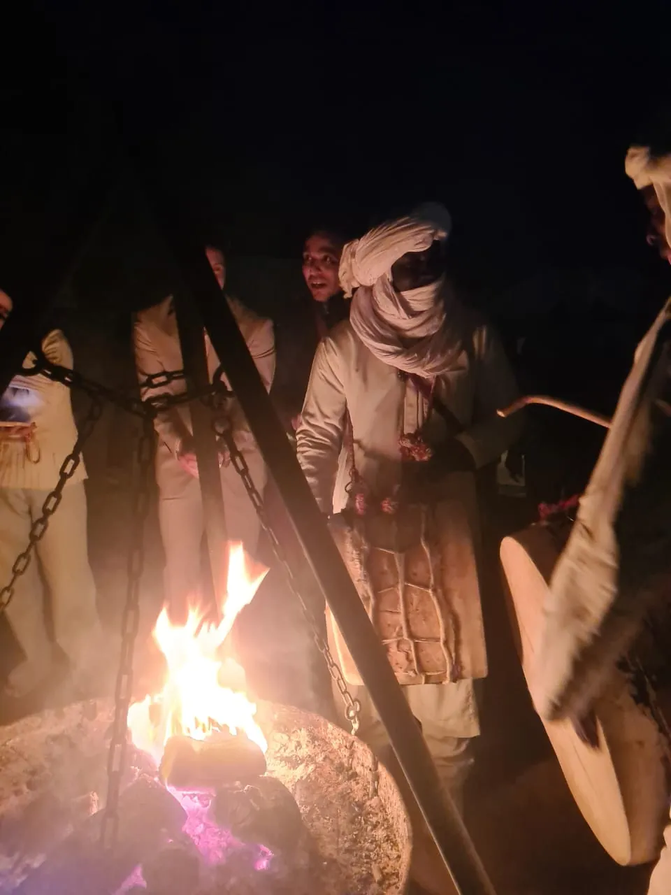 Guests gathered around the campfire with a musician at night