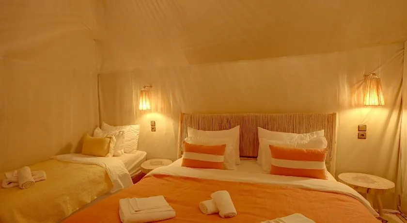 Tent room with a double bed and a single bed, lit by wall lamps