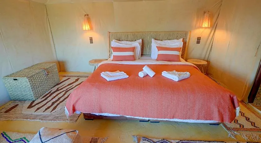 Double bed with terracotta throw inside a private desert tent