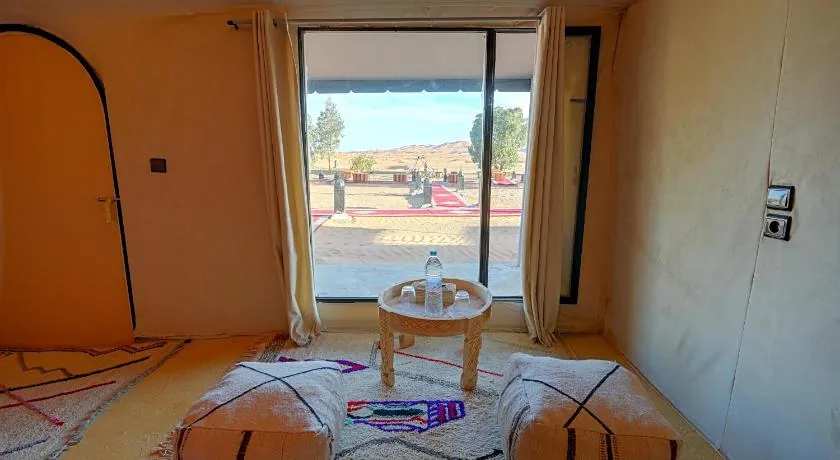 Seating area inside a tent with a glass door facing the dunes