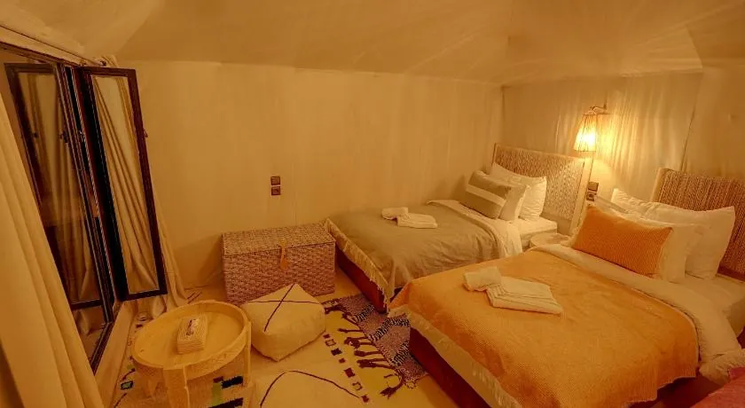 Tent room with two beds, woven headboards and warm wall lamps